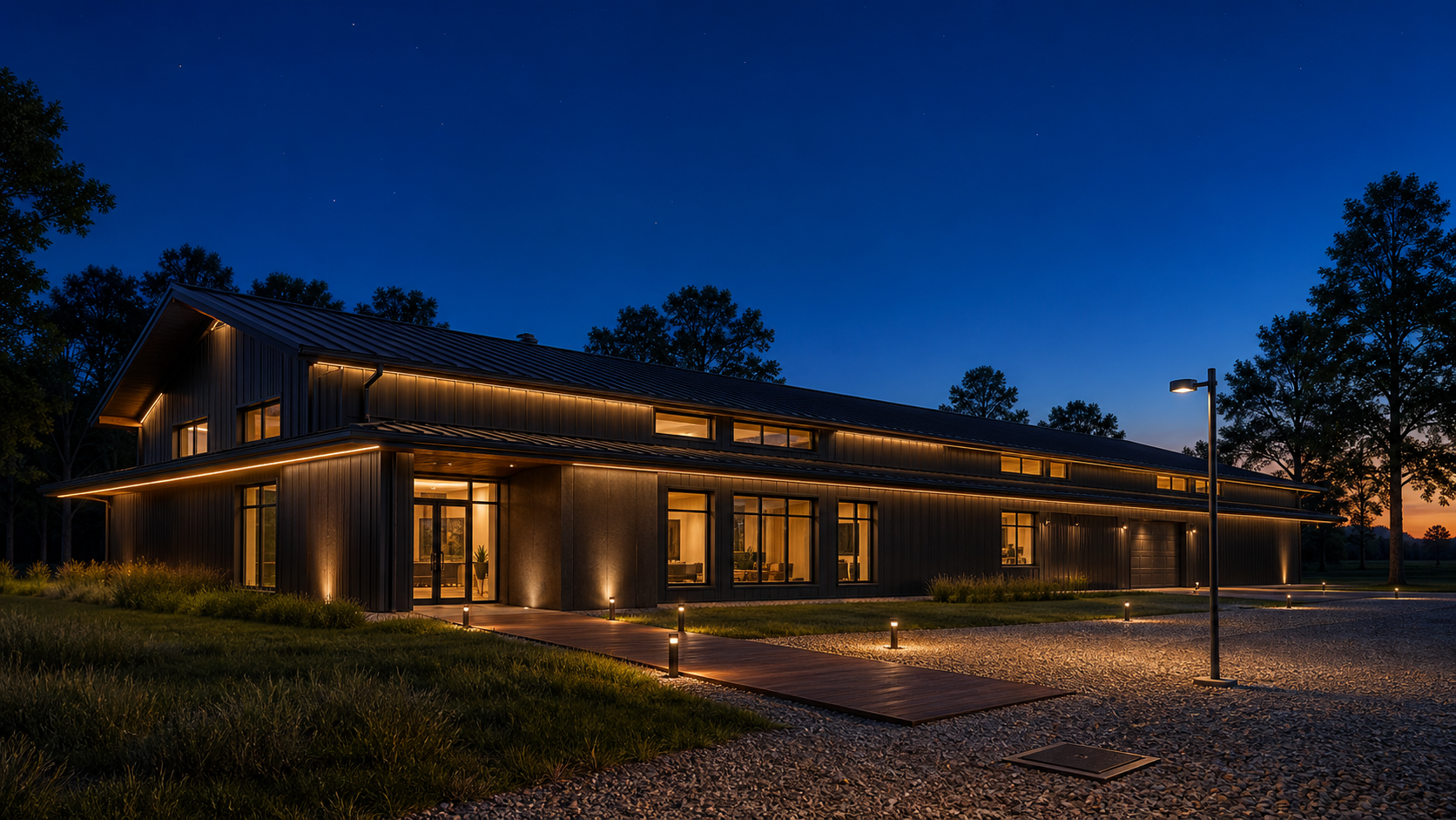 AI-rendered architectural visualization of the barndominium exterior at deep blue-hour dusk — long south elevation of the dark-bronze PEMB barn, continuous concealed soffit glow wrapping the eave underside as a luminous horizontal datum, disciplined low-voltage path bollards along an ipe walk, ground-recessed accent uplights at key vertical elements, soft warm interior spill through windows, cobalt sky